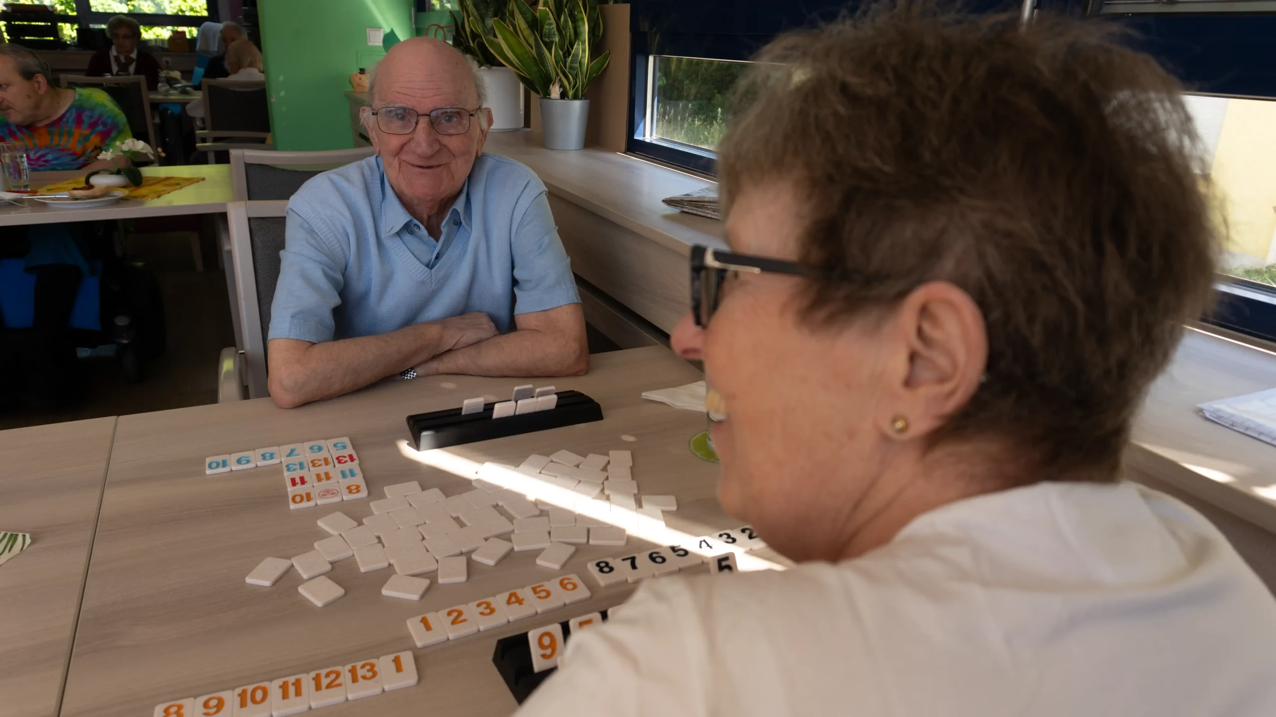 Rummikub-Steine auf dem Tisch vor Senioren