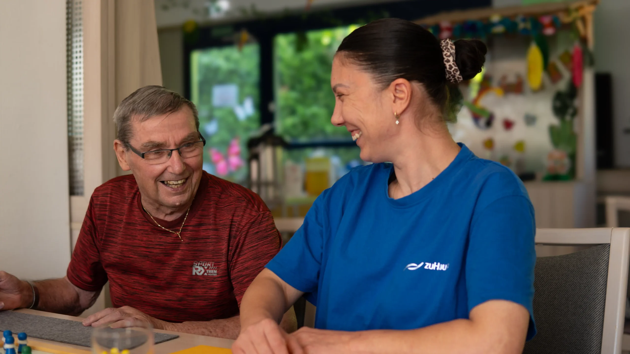 Pflegekraft und Senior lachen