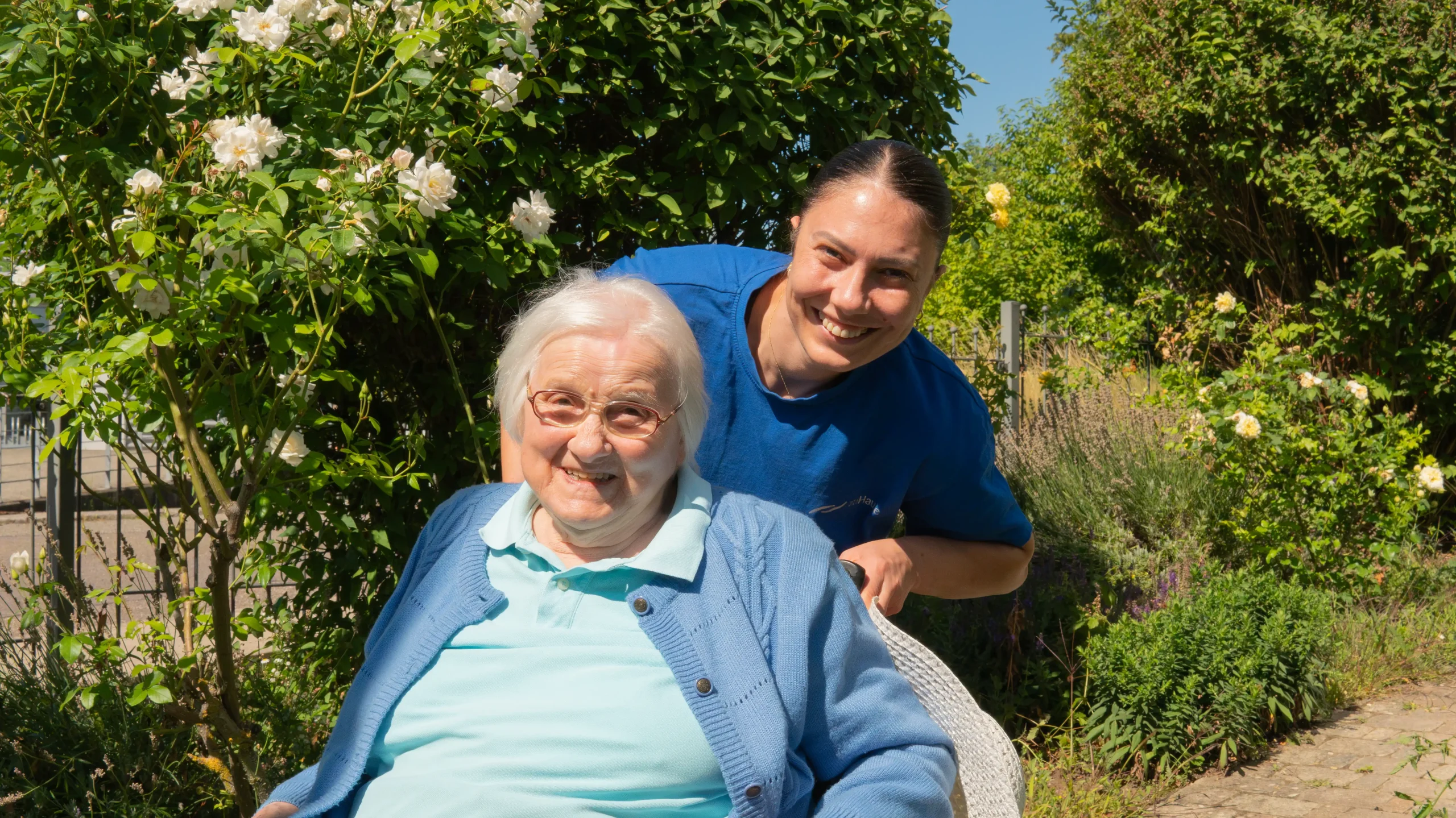 Pflegekraft und Seniorin im Garten
