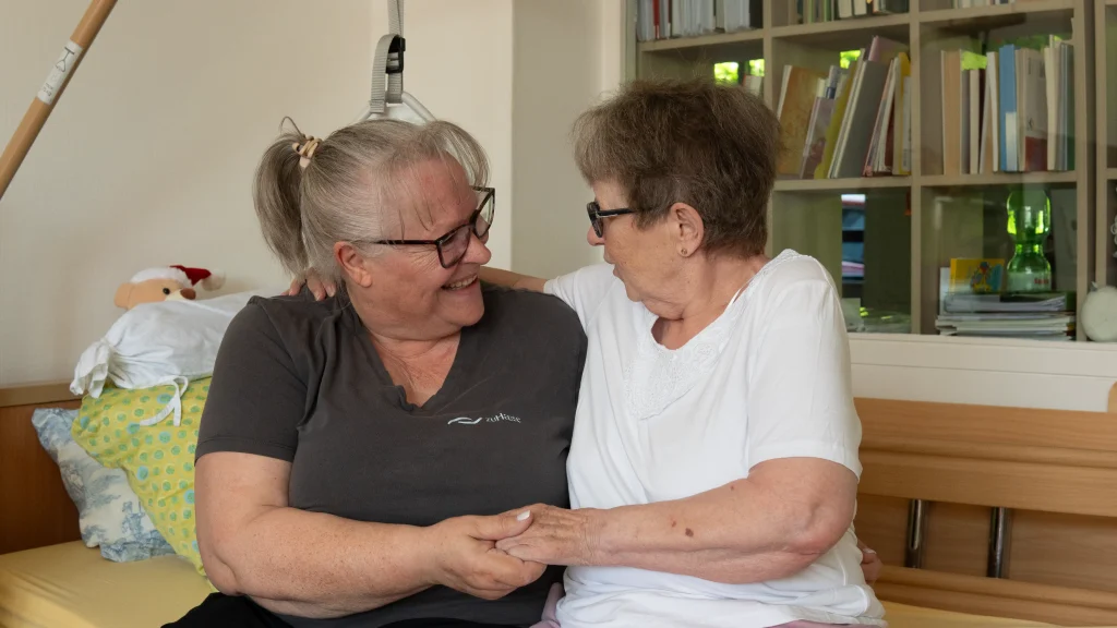 Pflegekraft und Seniorin umarmen sich