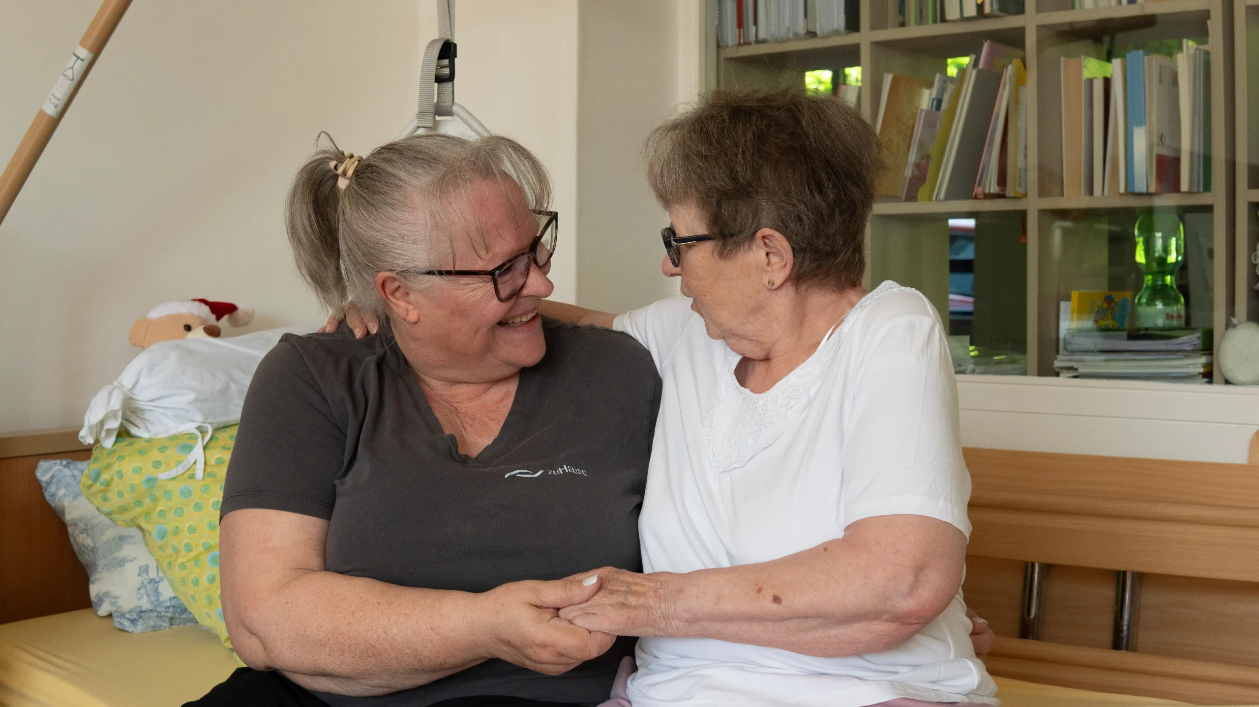 Pflegekraft und Seniorin umarmen sich